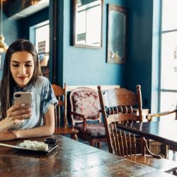 Young woman smiles while looking at mobile phone.
