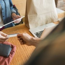 Customer hands store clerk their credit card.