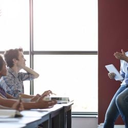 Female teacher calls on student raising his hand.