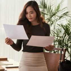A young woman looks over documents in her office.