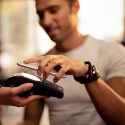 Man uses mobile phone to tap to pay on credit card reader.
