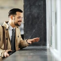A man stands at a counter window ready to buy a money order.