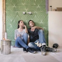 Couple renovating a new house, sitting on ground planning their bathroom