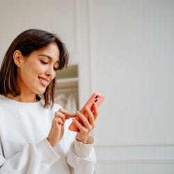 A woman smiling and checking her mobile phone.