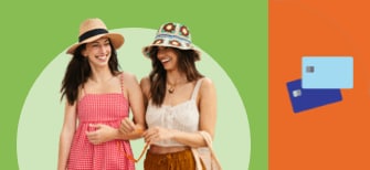 Two women in floppy hats and sundresses walk with arms linked