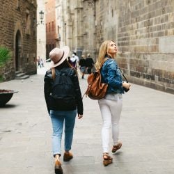Two women sightseeing near stone buildings
