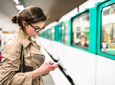 Woman checking which credit cards she qualifies for on a mobile device as she waits for her commute.