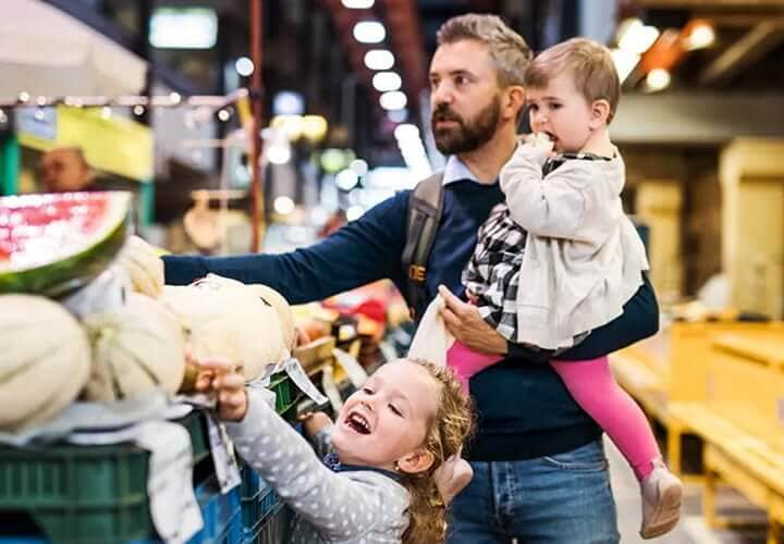 Man with children buying groceries uses Apple Pay on iPhone.