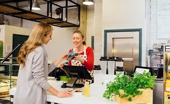 A woman using her debit card to pay for food at a restaurant.