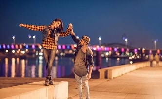 Man and woman walking along a city waterfront.