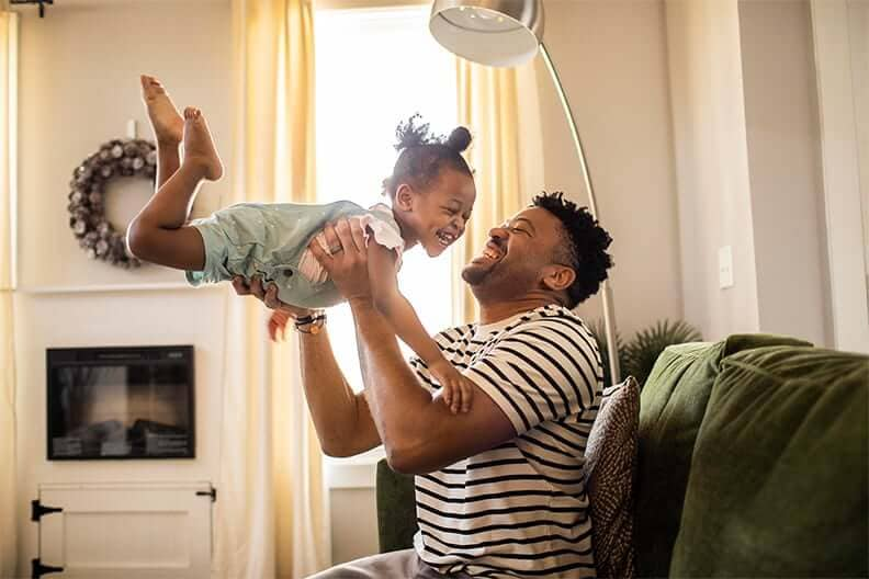 Father playfully swings daughter in the air after opening a CD account.