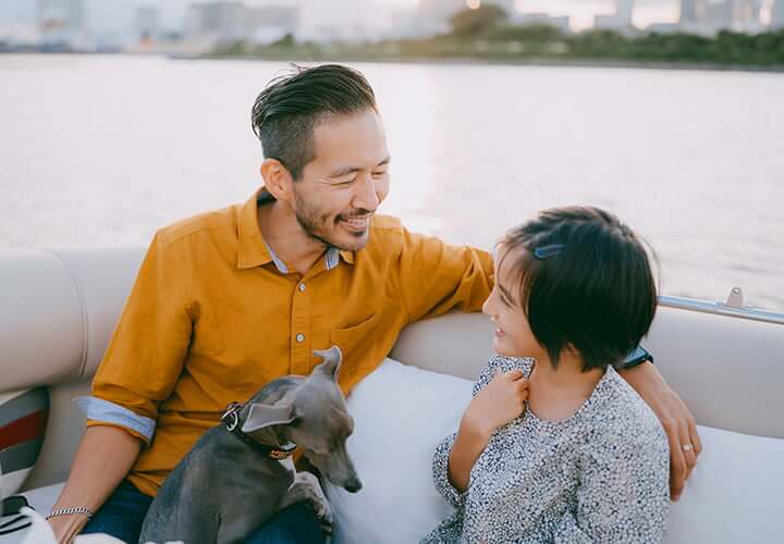 Father and daughter enjoy an afternoon boat ride with their dog.