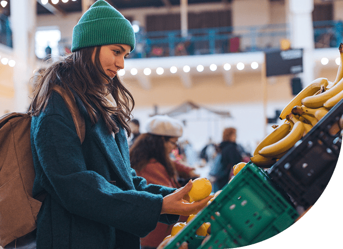 Young woman smiles while shopping for produce at a farmer's market.