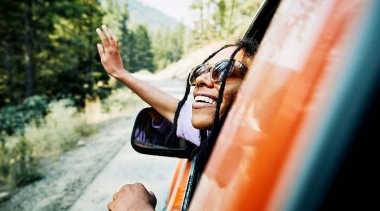 Woman waves to friend while driving to ATM machine to access her online bank account.