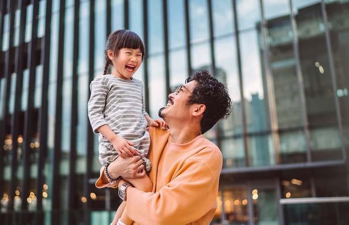 Father lifts his daughter into the air while considering online banking.