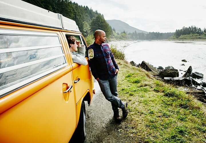 Couple on vacation discussing ways to save money while enjoying the view of a river.