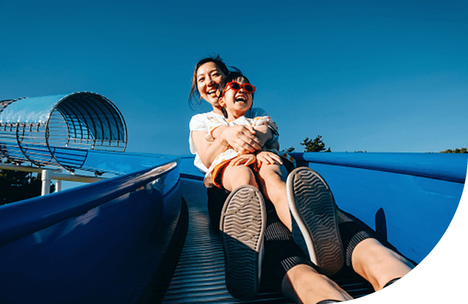 Woman and child smiling while riding a slide together.