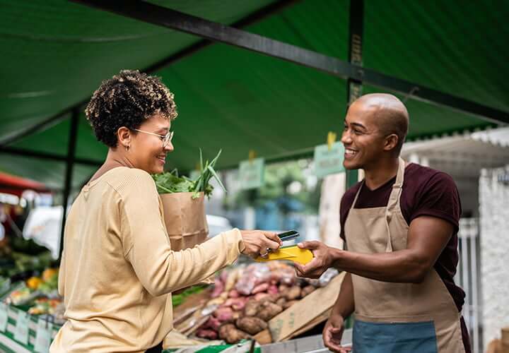 Woman uses Google Pay to buy vegetables from farmer's market.