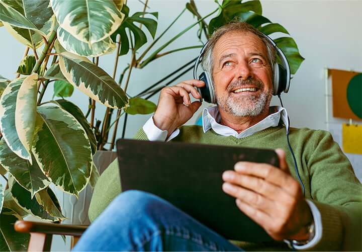 Man wearing headphones and holding tablet smiles because he just opened a money market account.