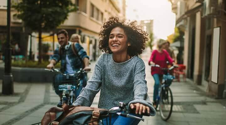 Young woman riding bike to ATM machine to access her money market account.