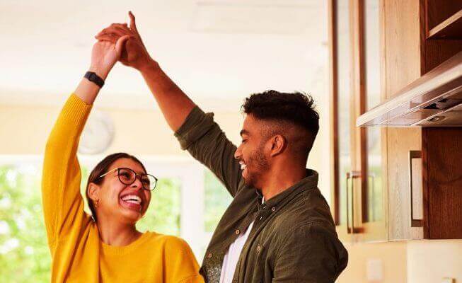 Woman and man dancing in their home after opening a money market account.