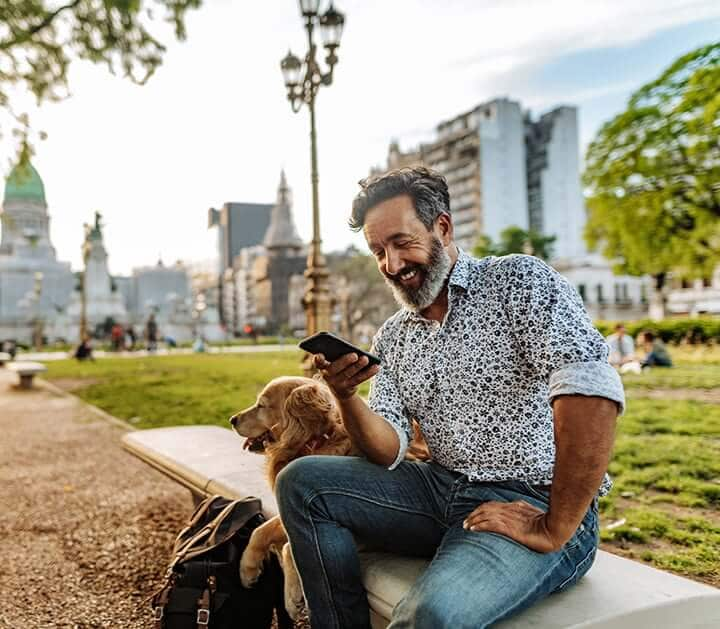 Man sitting on bench transfers money into his IRA using his mobile phone.