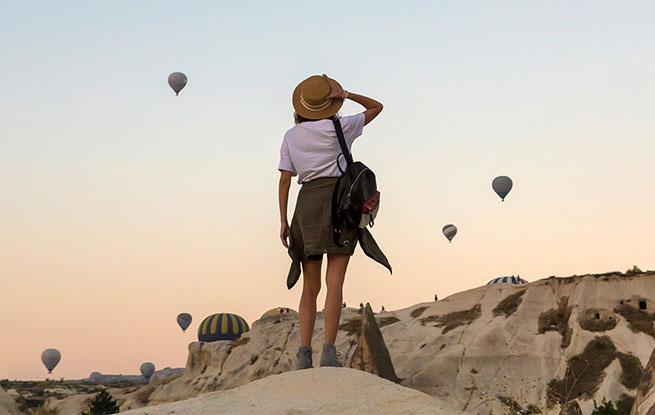Student on a hill looking at hot air balloons