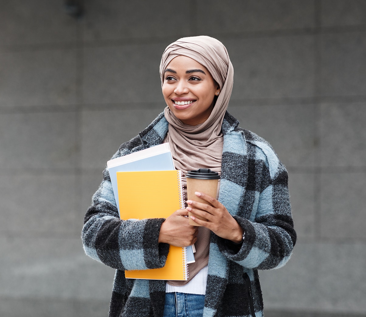 Female student holding notebook and a coffee 