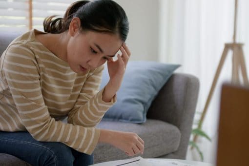 A woman is stressed while looking at her overdue bills.