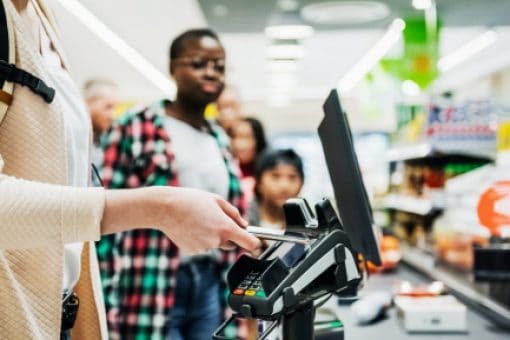 Woman using her digital wallet to pay at grocery checkout