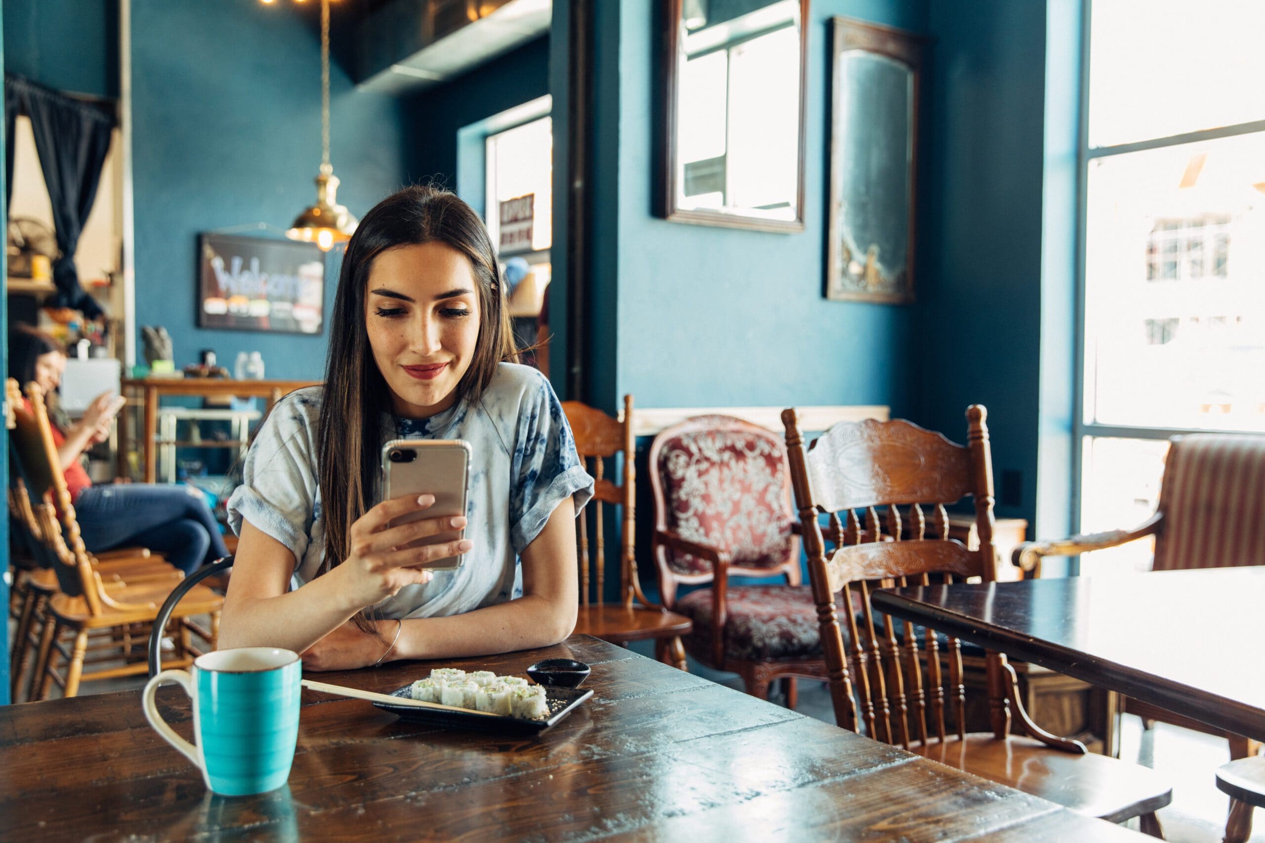 Young woman smiles while looking at mobile phone.