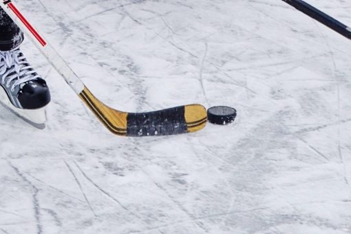 Closeup of hockey skate, stick and puck on ice
