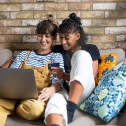 Woman holds a credit card and looks at a laptop screen with her partner.