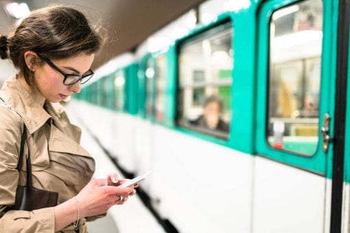 Woman on her phone stands next to a commuter train