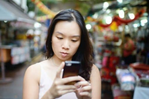 Woman at street market looks at her phone.