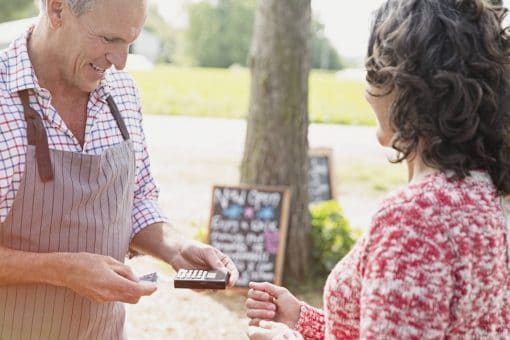 Flea market shop owner helps customer pay with credit card