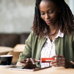 Woman uses tablet to check credit card rewards.