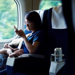 A young mother holds her baby and browses on her phone.