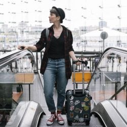 Woman rides an escalator holding a rolling traveling suitcase