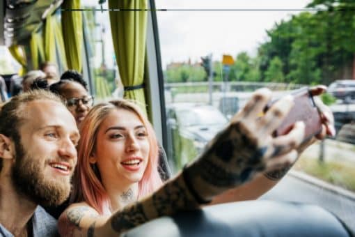 A young couple traveling on a bus takes a selfie photo together.