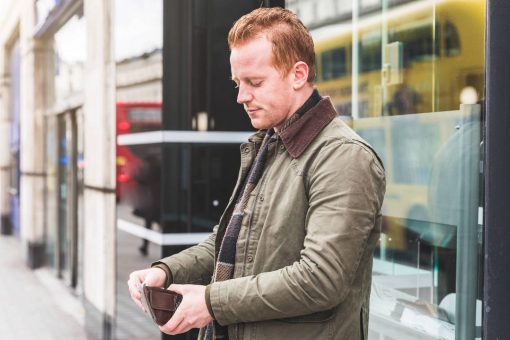 Man opening wallet on street outside an office building