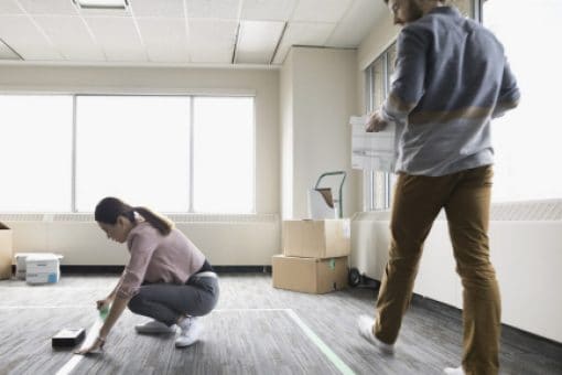 A man and a woman measure space for their new office