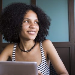 Woman smiles as she holds a digital tablet.