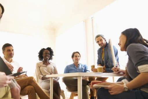 A group of people sit around a table at a cafe laughing.