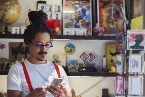 Young professional looks down at his mobile phone while inside a gift shop.