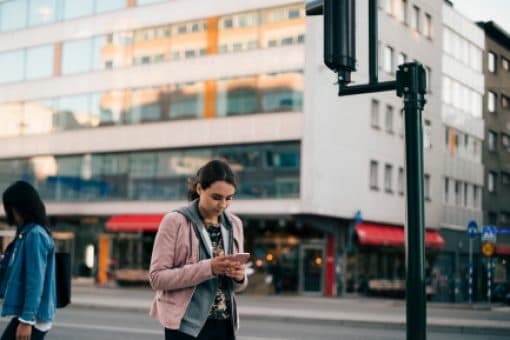 Women looking at their mobile phones pass one another on a quiet city street