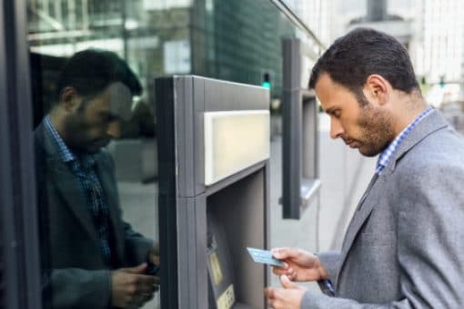 Man gets ready to insert credit card into ATM machine on street