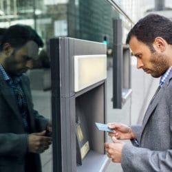 Man gets ready to insert credit card into ATM machine on street