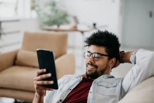 Man reclines in his home looking at phone