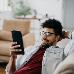 Man reclines on his sofa while shopping online with his tablet.